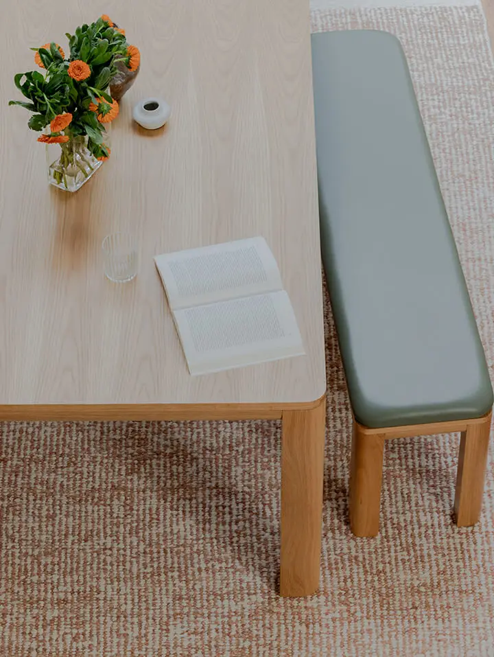 Frankie Dining Table and Bowie bench seat in American oak with olive leather seat pad and orange and green flowers