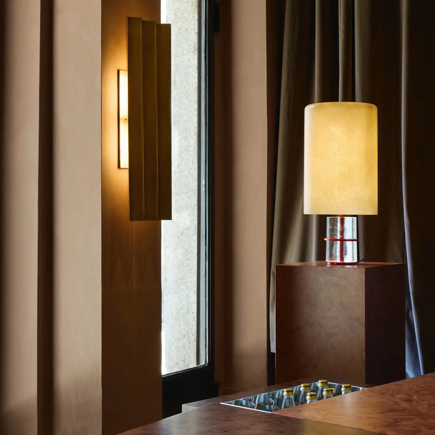 Dark and moody interior space from an exhibition in Milan with large fiber glass pendant lights with brass detailing, along with rich timber finishes